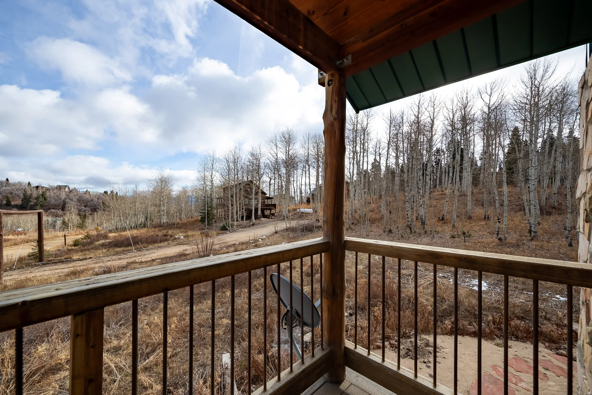 Covered deck featuring wood posts, a wood railing with metal balusters, and a green metal roof