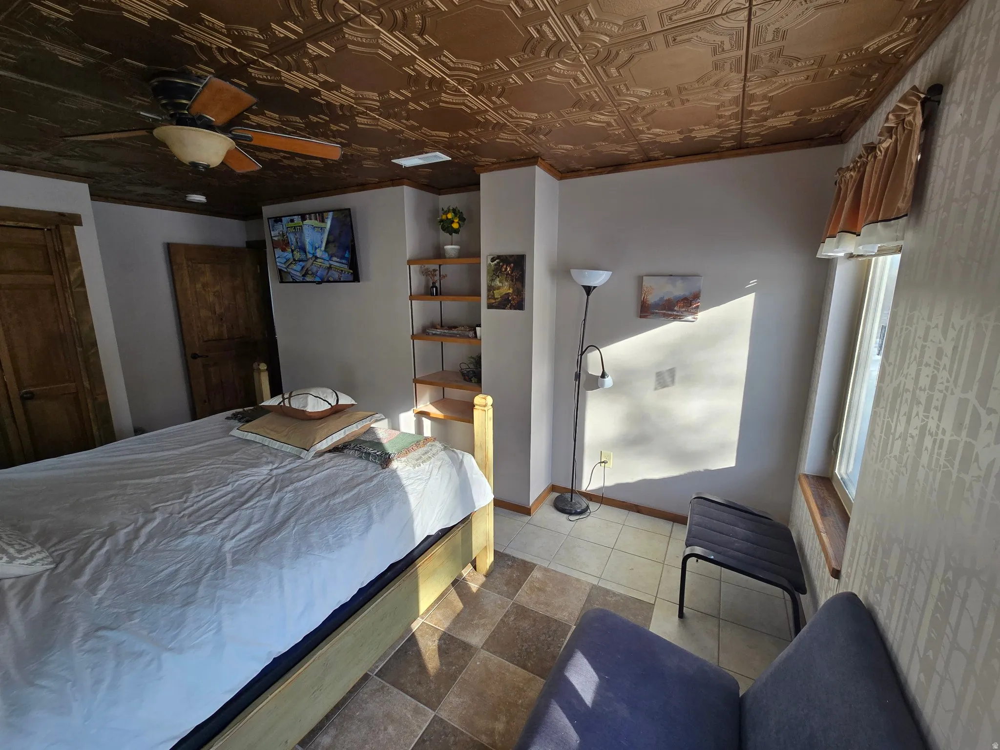 Recessed ceiling with decorative panels, wood-finish ceiling fan, wood-finish doors, built-in shelving, and tile flooring