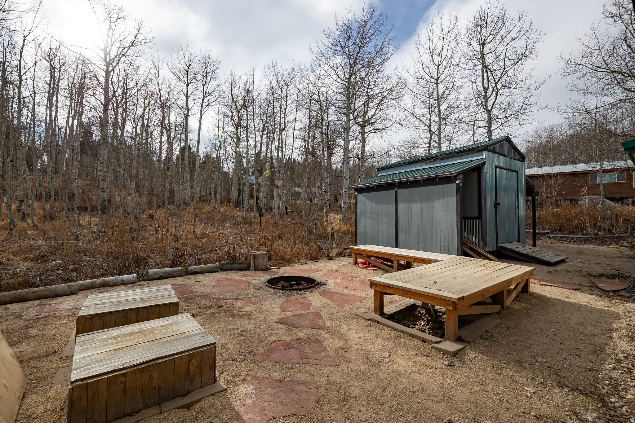 Outdoor area featuring a fire pit, flagstone patio, and a storage shed with a ramp entrance