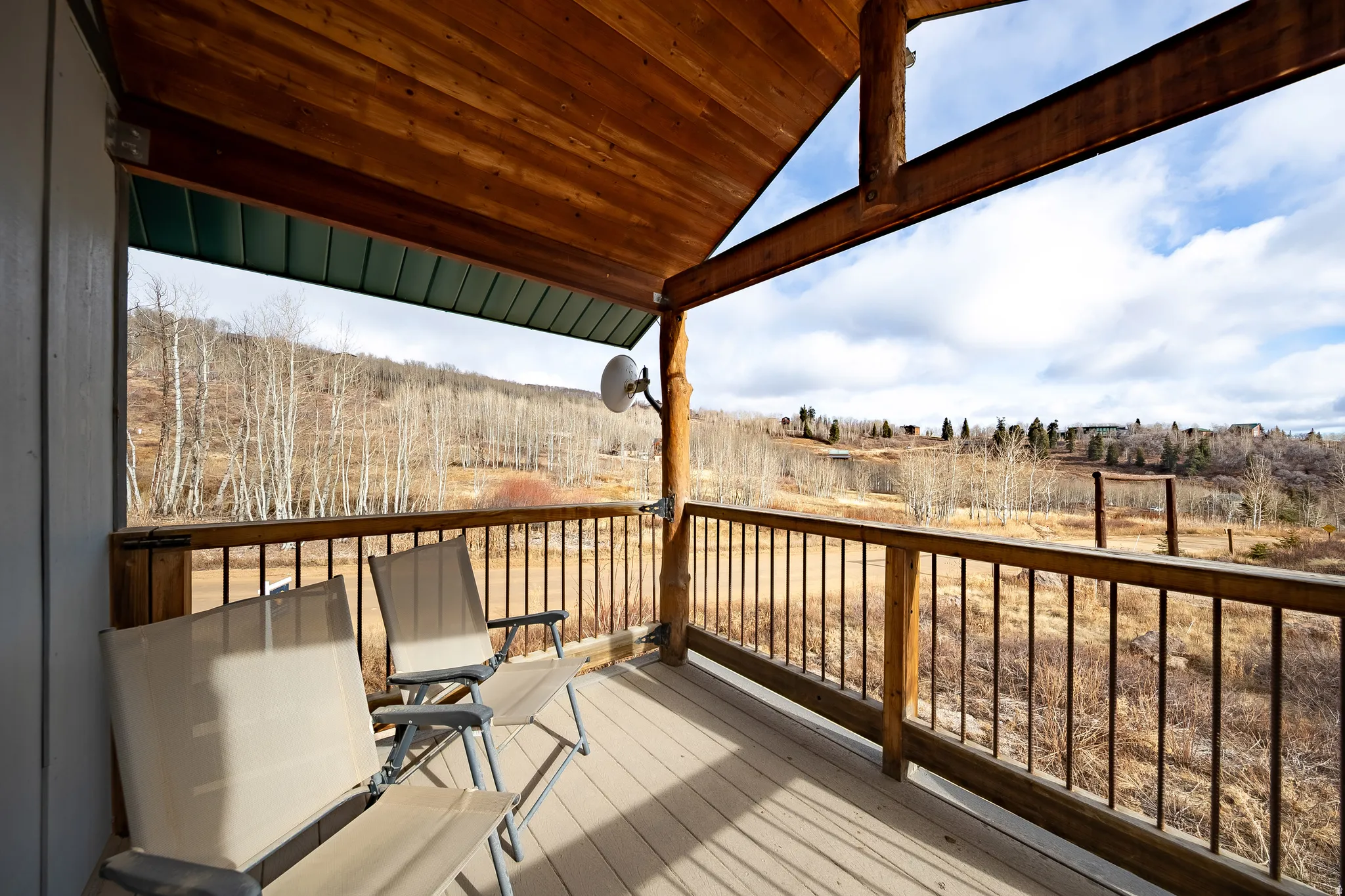 Covered wood-finish deck with log columns, wood-finish ceiling, and metal railings