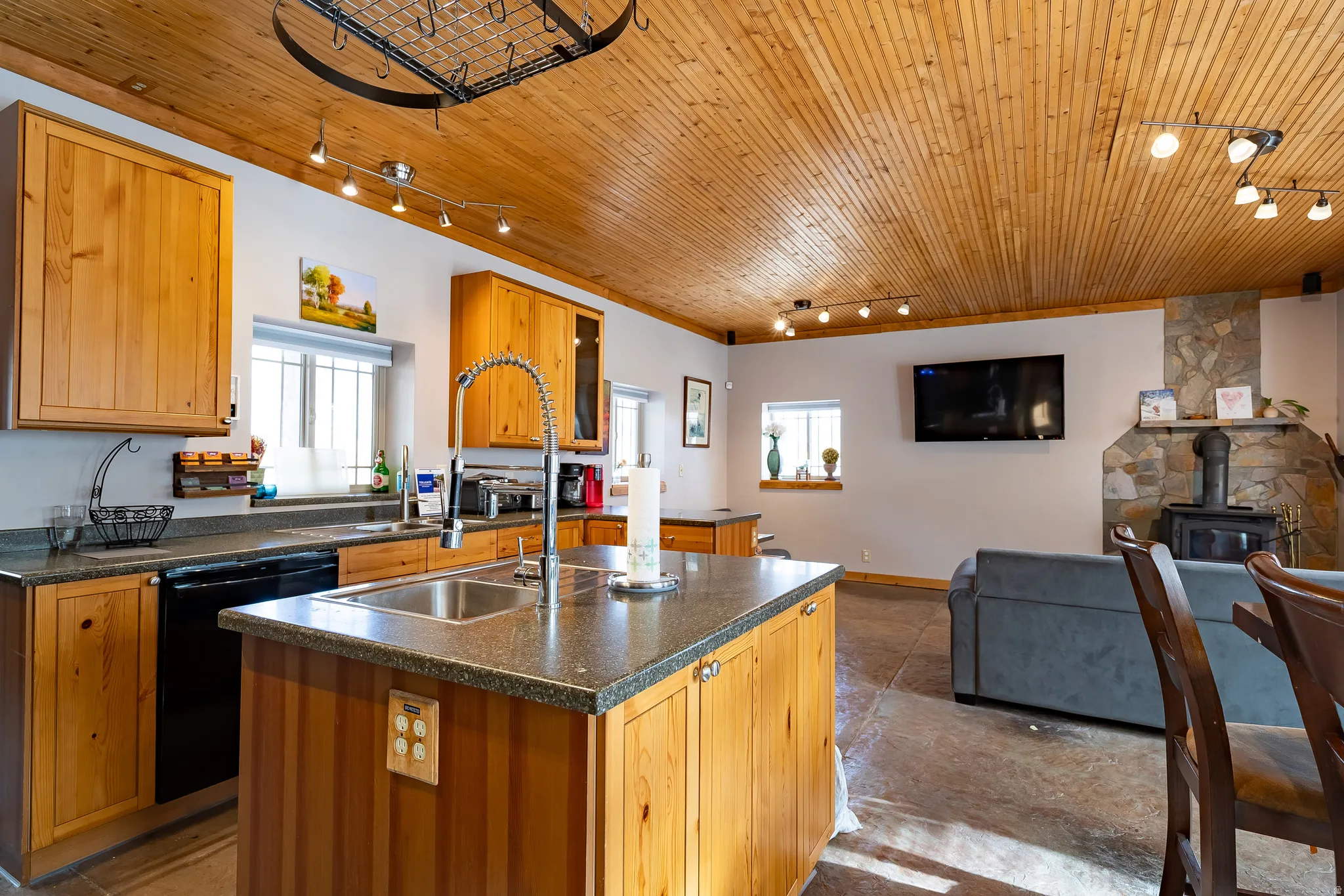 Kitchen island with an undermount sink, wood cabinetry, and track lighting