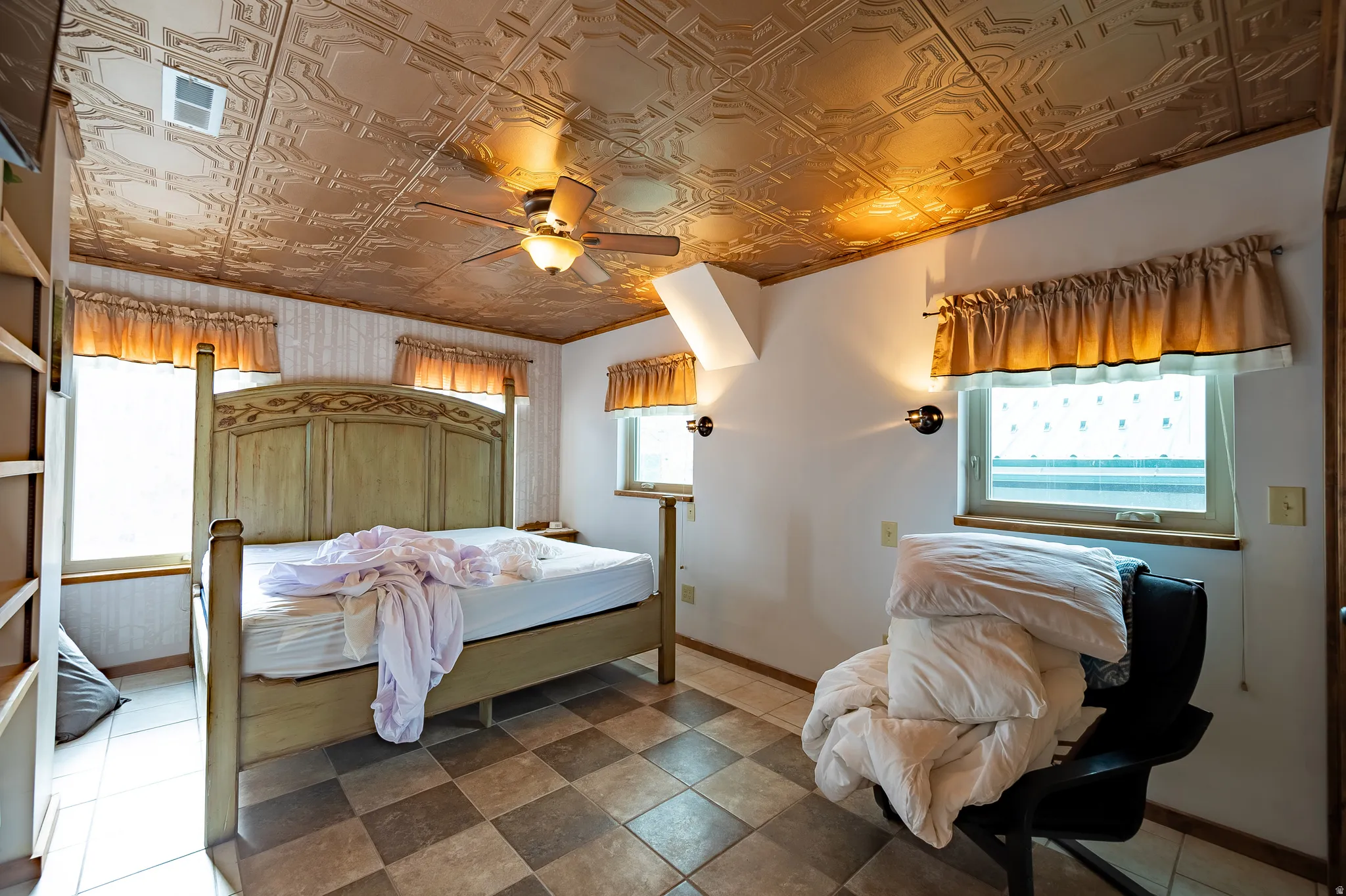 Pressed tin-style ceiling, ceiling fan with integrated lighting, built-in shelving, checkered tile flooring, and wall-mounted sconces