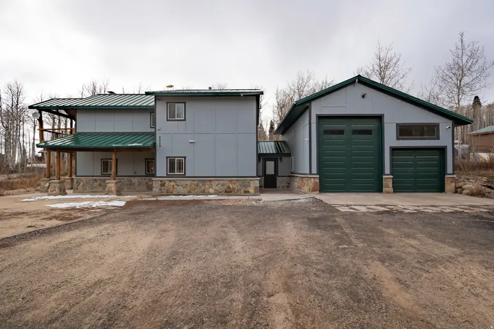 Two-story residence with a covered porch, stone veneer foundation, and a detached two-door garage