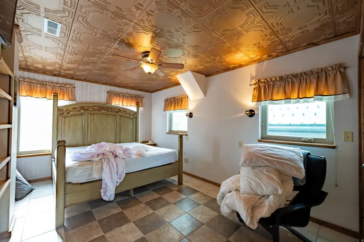 Pressed tin-style ceiling, ceiling fan with integrated lighting, built-in shelving, checkered tile flooring, and wall-mounted sconces