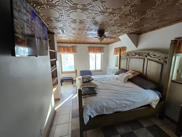 Decorative ceiling fan, built-in shelving, tiled flooring, wood-framed windows, and a decorative ceiling