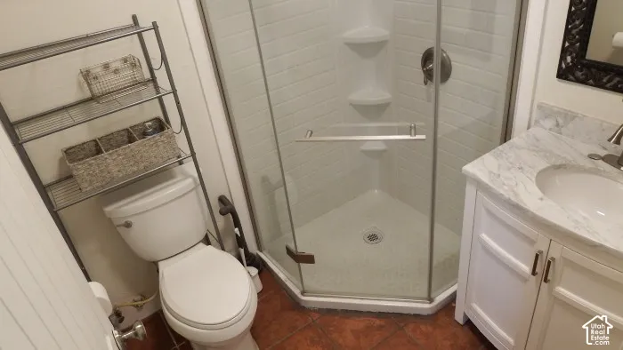 Corner shower with glass enclosure, white subway tile surround, white cabinet vanity with integrated sink, and stone countertop