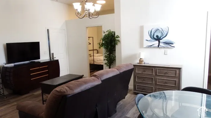 Vaulted ceiling, ceiling-mounted chandelier, wood-finish flooring, glass-top table