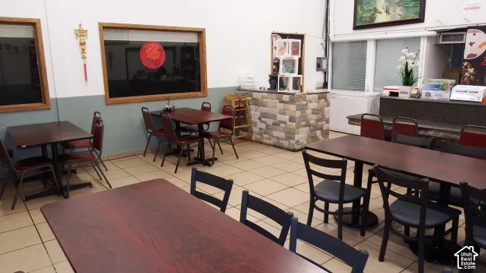 Tiled flooring throughout, wood-finish tables, stone-clad counter, and recessed lighting