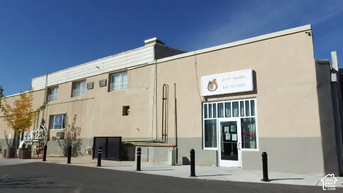 Two-story commercial building with a stucco exterior, multiple window units, and a ground-level storefront with large display windows