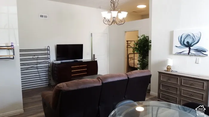 Vaulted ceiling with a chandelier, wood-finish flooring, and white interior walls