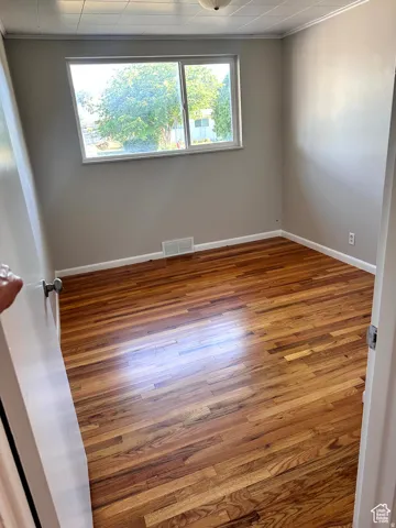 Hardwood flooring, neutral wall paint, and a white-framed window