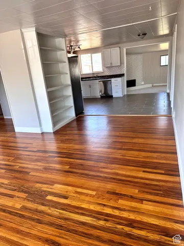 Hardwood flooring, built-in shelving, white cabinetry, dark tile flooring, and a stainless steel dishwasher