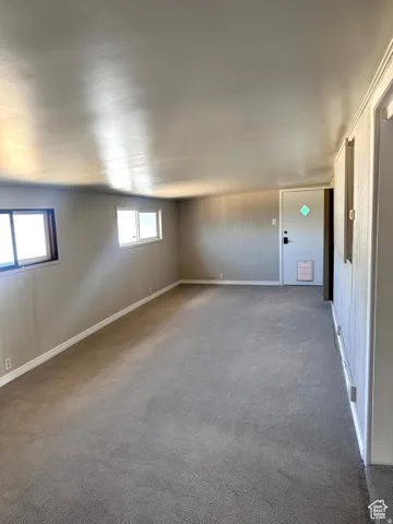 Spacious room featuring neutral carpeting, light-colored walls, and multiple windows