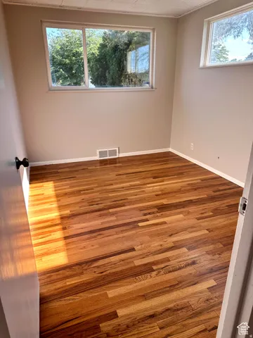 Hardwood flooring, neutral painted walls, white trim, and multiple windows