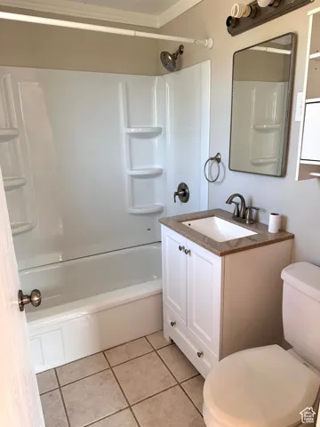 Bathroom featuring a shower/tub combination, white vanity with an integrated sink, stone-finish countertop, and tiled flooring