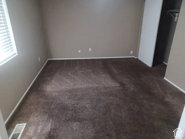 Neutral-toned walls, wall-to-wall carpeting, window with blinds, and an integrated closet with shelving