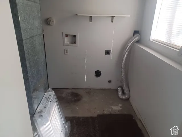 Dedicated utility area featuring washer and dryer hookups, flexible dryer venting, and wall-mounted shelving