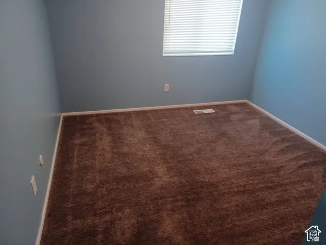 Interior room featuring wall-to-wall carpeting and a window with horizontal blinds