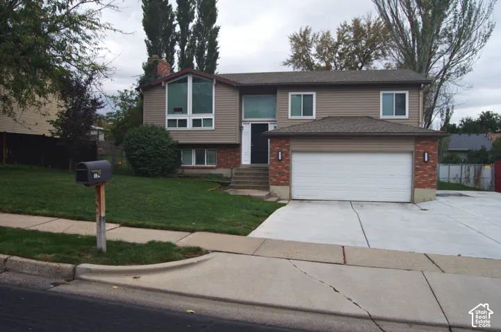 Split-level exterior featuring horizontal siding, brick masonry, an attached two-car garage, and large multi-pane windows
