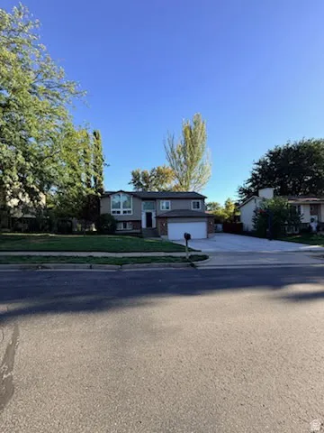 Split-level residence featuring a two-car garage, mature landscaping, and a concrete driveway