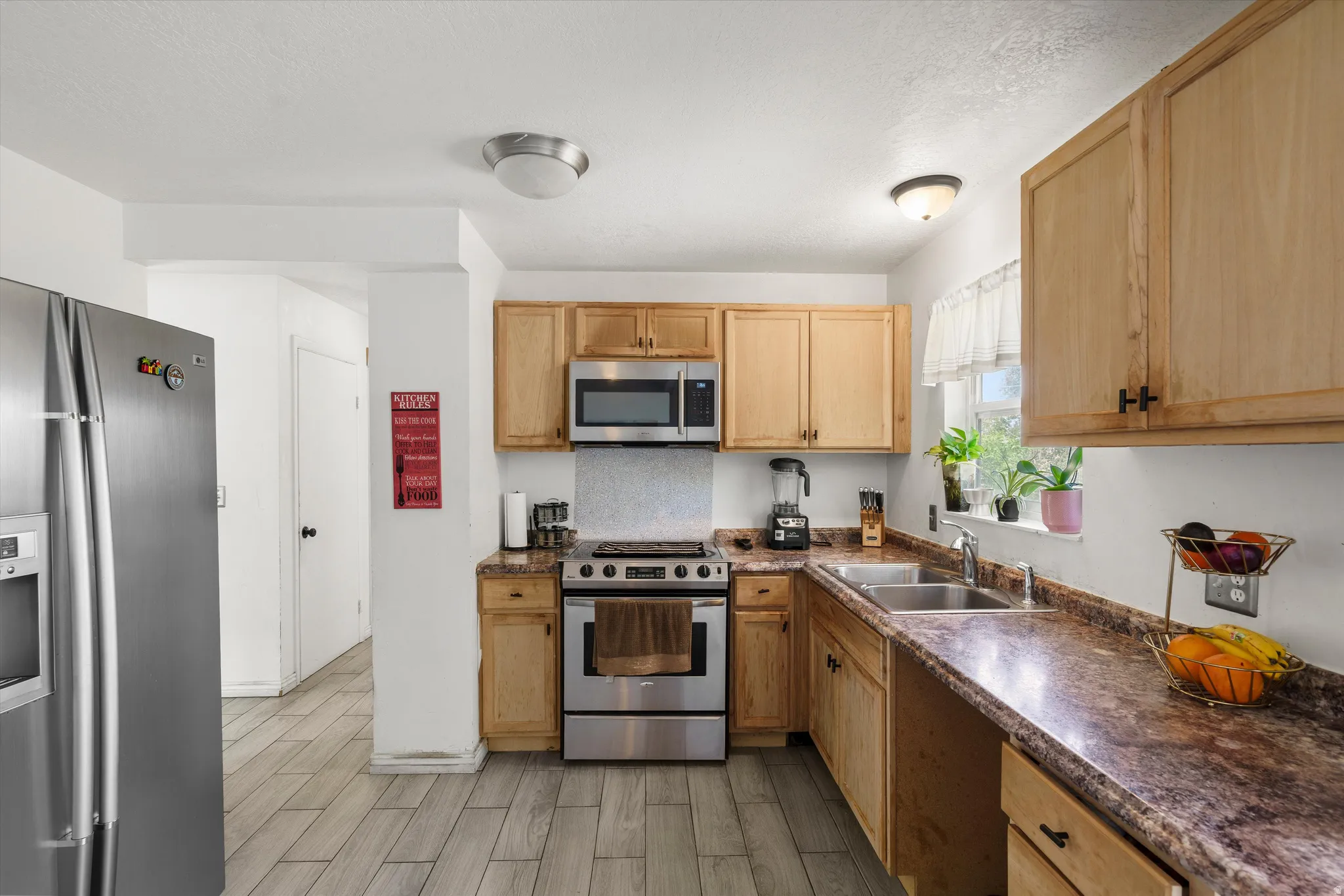 Wood-finish tile flooring with a stainless steel range, microwave, and refrigerator