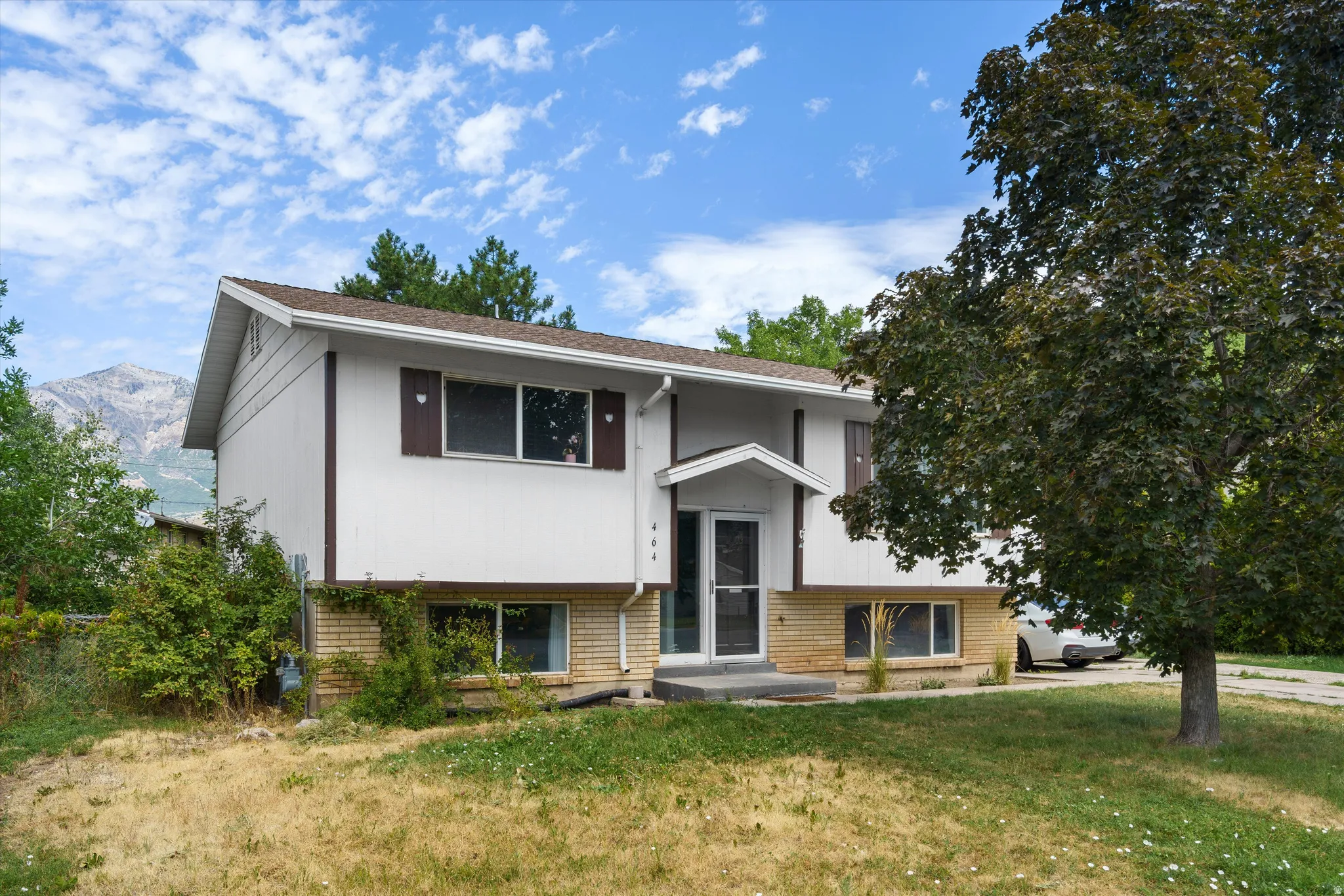 Split-level residence featuring a white exterior, brick accents, and a covered entry
