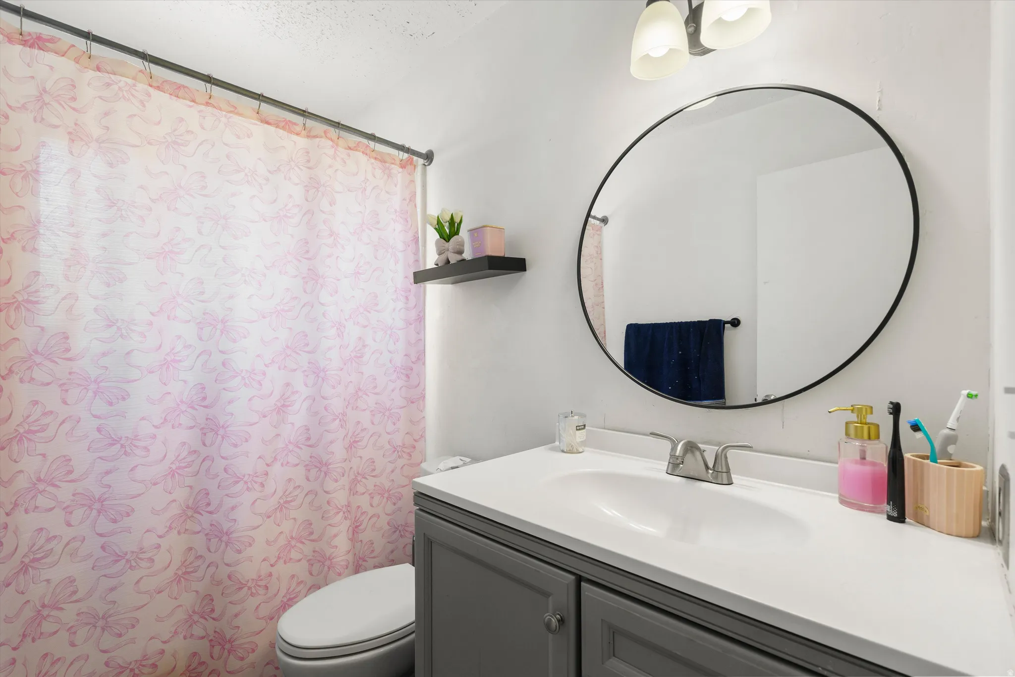 Vanity with gray cabinetry, white countertop, and integrated sink
