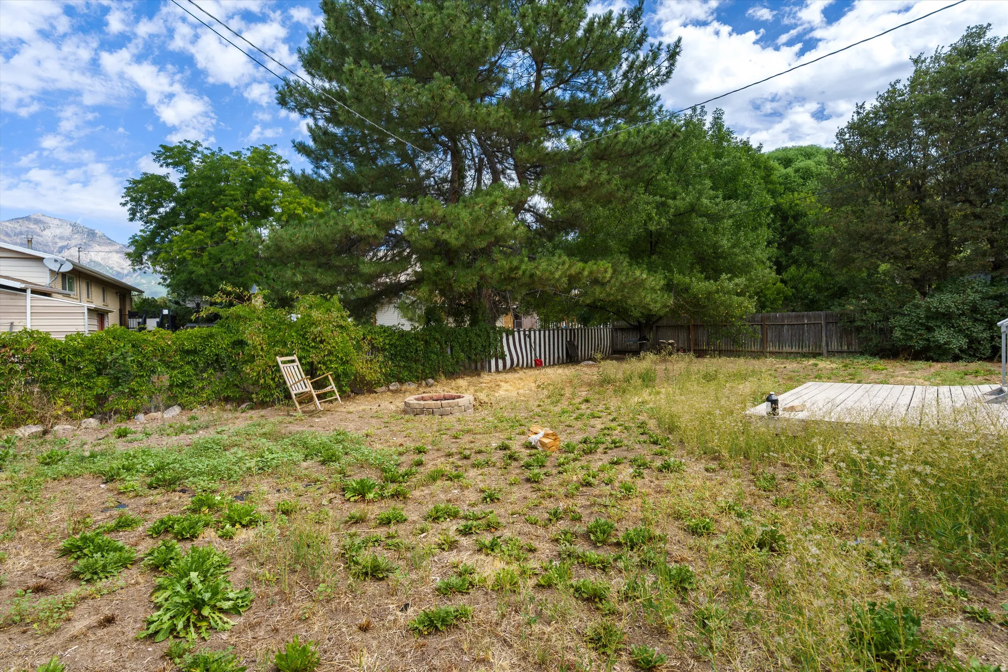 Expansive yard featuring mature trees, a wood deck, and a stone fire pit