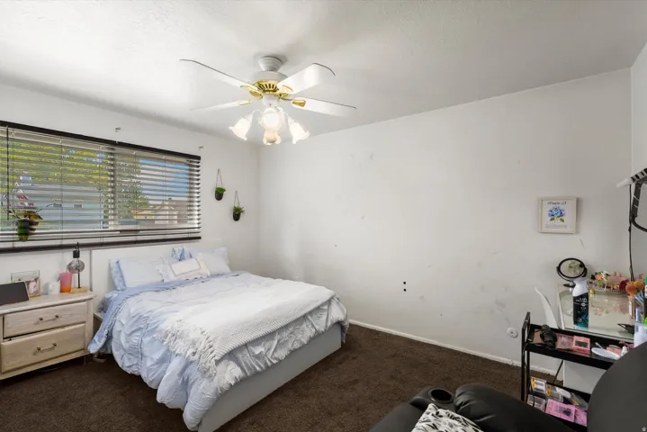 Window with horizontal blinds, ceiling fan with integrated lighting, and textured ceiling finish