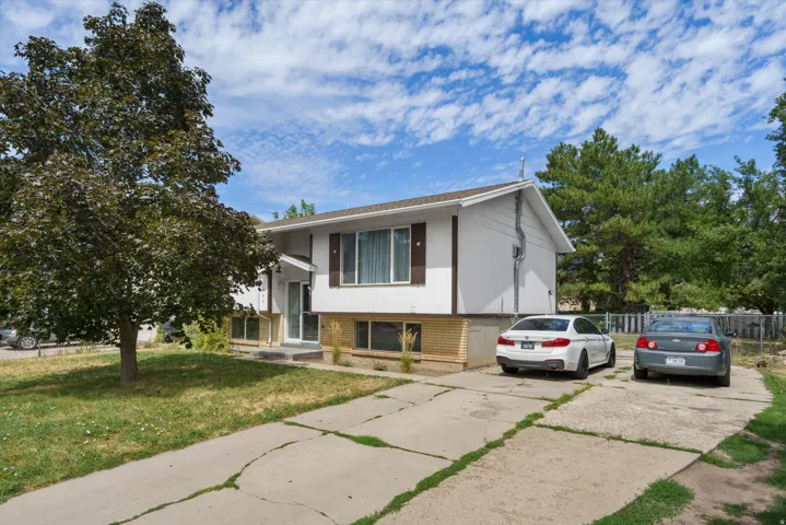 Split-level residence featuring a concrete driveway and mature trees
