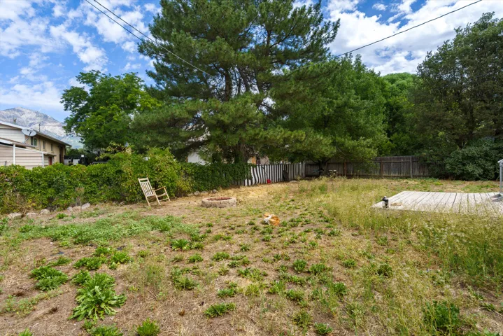 Expansive yard featuring mature trees, a wood deck, and a stone fire pit