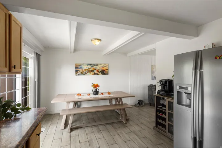White exposed beam ceiling, Wood-finish tile flooring, glass-paned sliding door, stainless steel refrigerator, and integrated wine storage