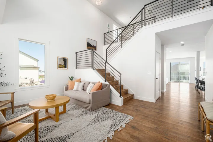 Vaulted ceilings, wood-finish flooring, staircase with horizontal metal balusters, white trim, and a large window