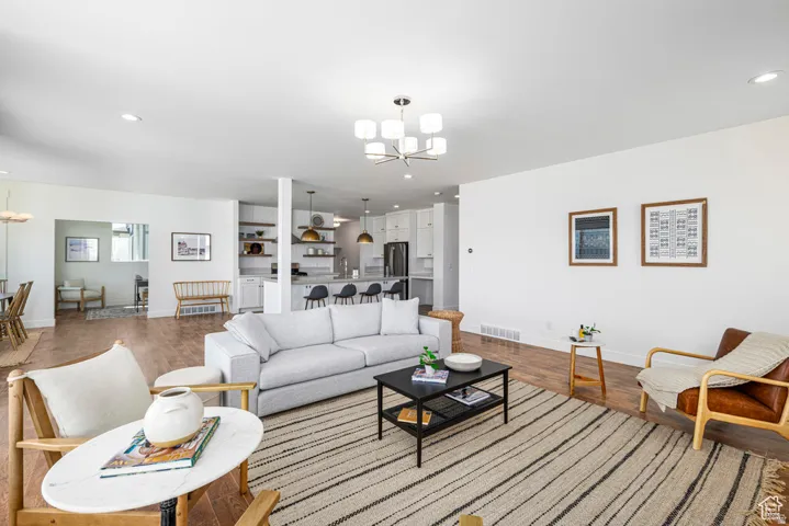 Open-concept living area with wood-finish flooring, recessed lighting, and a contemporary chandelier