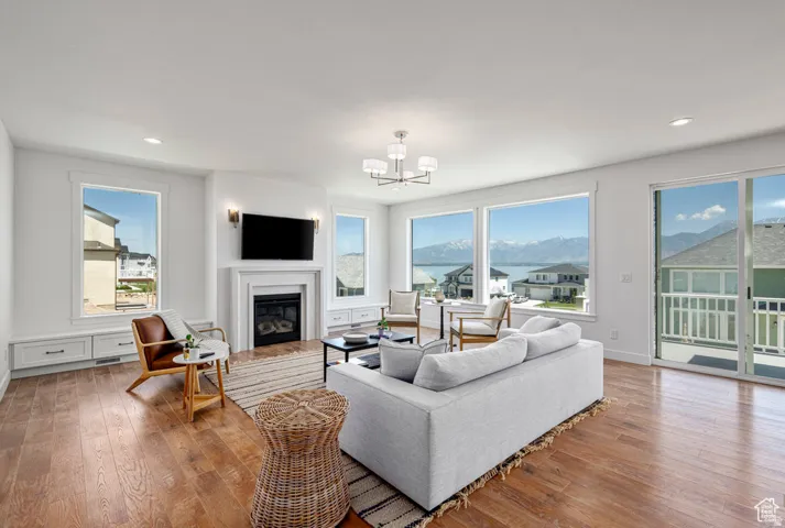 Spacious living area featuring wood-finish flooring, a fireplace with a mantel, built-in cabinetry, and large windows