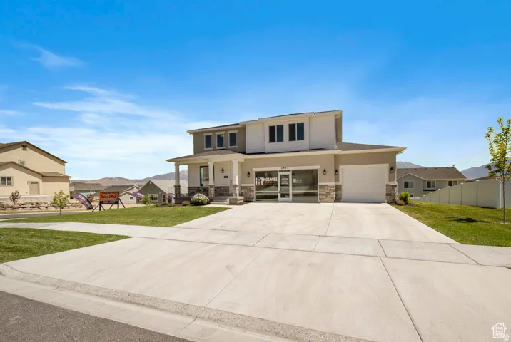 Two-story residence featuring a covered entry, stone column accents, an attached garage, and a concrete driveway