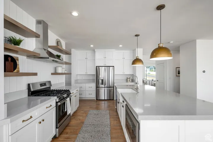 Contemporary kitchen featuring quartz countertops, white cabinetry, stainless steel appliances, open wood-finish shelving, and two pendant light fixtures