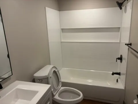 White tiled shower with built-in niche, white bathtub, matte black shower fixtures, vanity with integrated sink, and wood-finish flooring