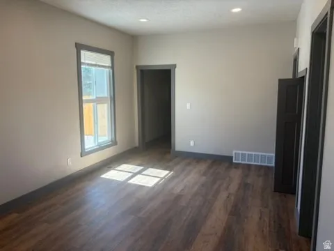 Wood-finish flooring, recessed ceiling lighting, neutral wall paint, and dark trim details