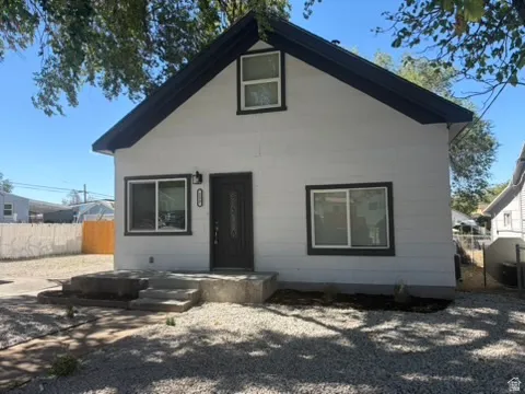White exterior with dark trim, featuring a dark entry door with decorative glass