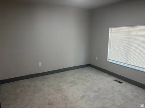 Neutral wall color with contrasting baseboards, carpeted flooring, and window with blinds