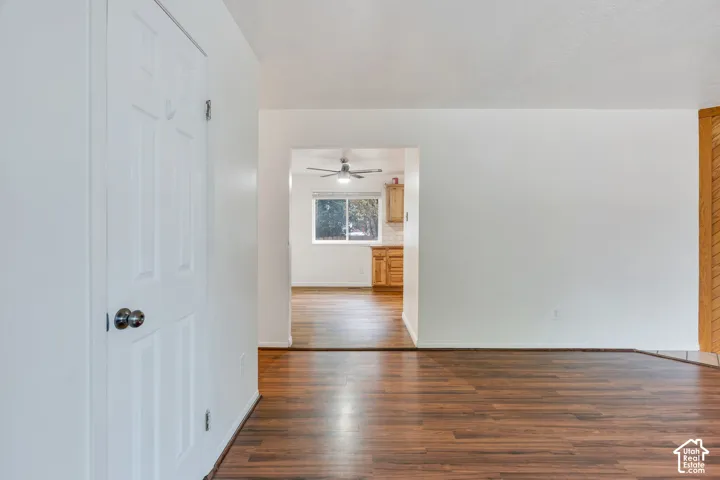 Interior featuring wood-finish flooring, a six-panel door, and a ceiling fan
