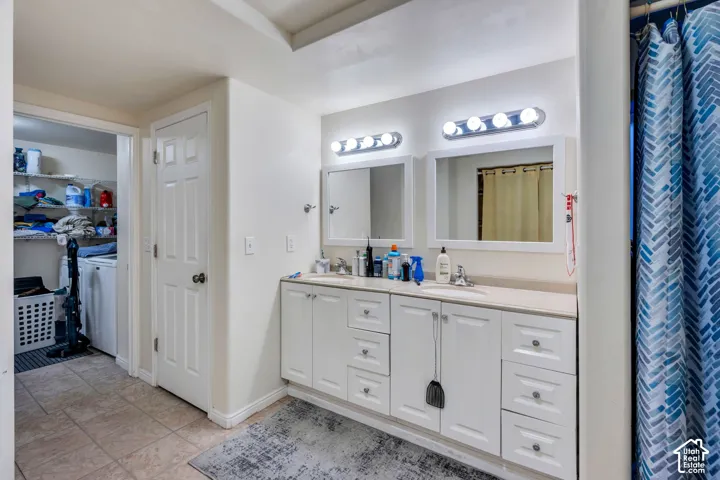 Double vanity featuring white cabinetry, integrated sinks, twin mirrors with white frames, and wall-mounted light fixtures