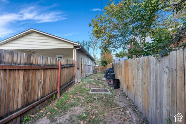 Side yard area enclosed by vertical wood privacy fencing and featuring mature trees