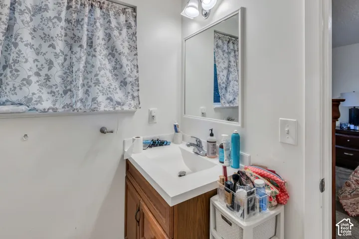 Bathroom vanity featuring a solid surface countertop with an integrated sink, wood-finish cabinetry, a wall-mounted mirror, and overhead lighting fixture
