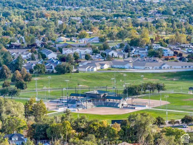 Aerial perspective showcasing an expansive public recreational park featuring multi-diamond baseball fields, stadium-style spectator seating, integrated floodlight towers, and perimeter walking paths set within a green space canopy