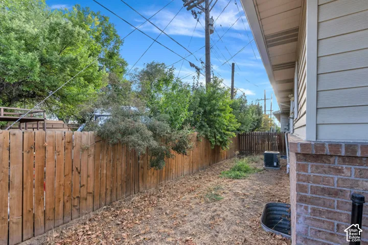 Exterior side yard featuring horizontal wood fencing, brick foundation accents, and horizontal siding