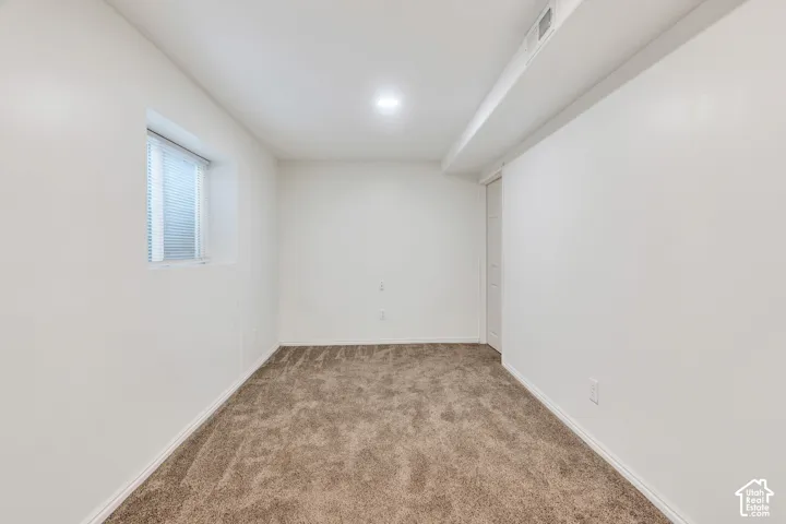 Neutral wall finishes, recessed ceiling lighting, textured wall-to-wall carpeting, and a single-pane window with integrated blinds