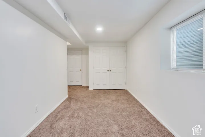 Neutral-toned interior space featuring carpeting, recessed lighting, double-door closet cabinetry, and a high-set rectangular window