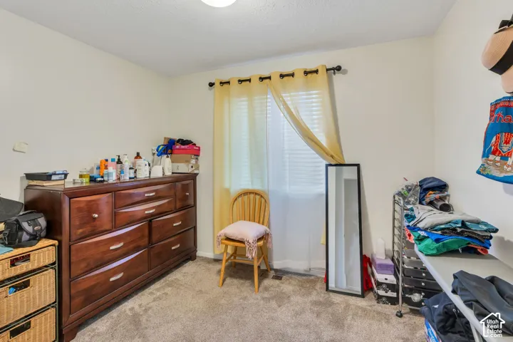 Room interior featuring neutral walls, wall-to-wall carpeting, and a window with horizontal blinds